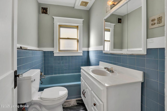 full bathroom with tile walls, toilet, wainscoting, a bath, and vanity