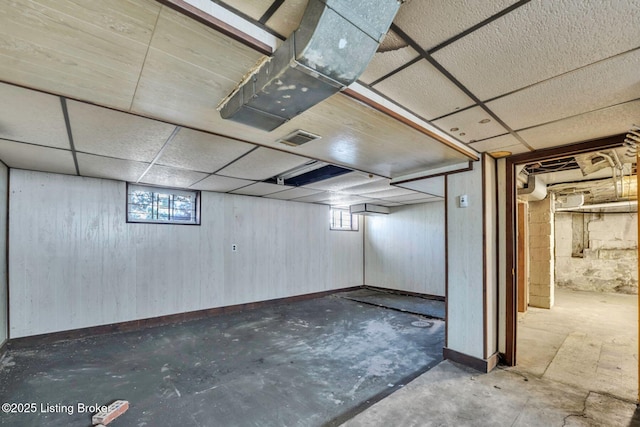 basement with a drop ceiling, visible vents, and a healthy amount of sunlight