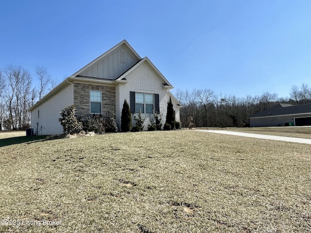 view of front of home featuring stone siding, central AC unit, board and batten siding, and a front yard