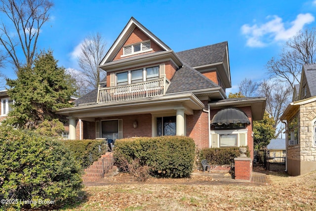 view of front of house featuring brick siding, roof with shingles, and a balcony