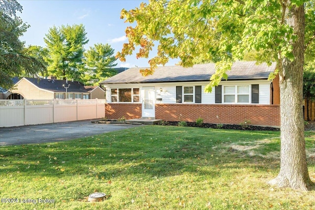 single story home featuring brick siding, a front lawn, and fence