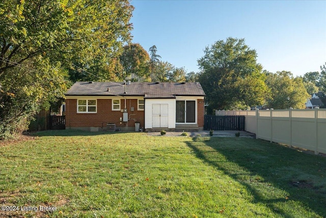 rear view of house featuring brick siding, a lawn, and a fenced backyard