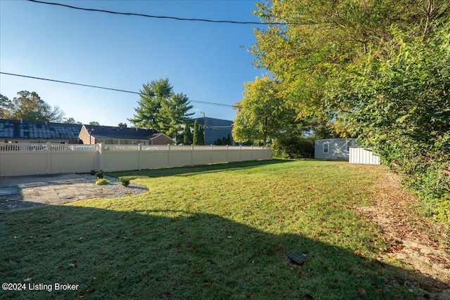 view of yard featuring a storage shed, fence, and an outbuilding