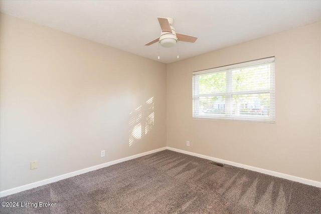 unfurnished room featuring ceiling fan, visible vents, baseboards, and dark colored carpet