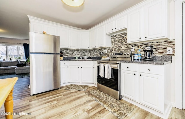 kitchen with stainless steel appliances, dark countertops, tasteful backsplash, light wood-style flooring, and white cabinetry