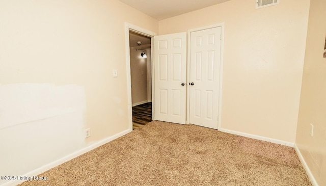 unfurnished bedroom featuring carpet, a closet, visible vents, and baseboards