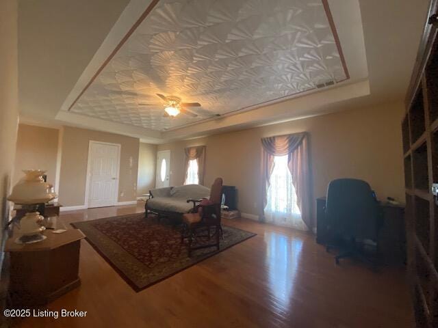 interior space with baseboards, a tray ceiling, and wood finished floors