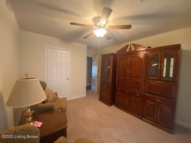 sitting room with a ceiling fan, light colored carpet, and baseboards