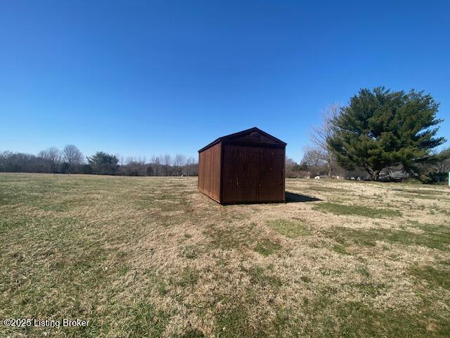 view of yard featuring a rural view, a storage unit, and an outdoor structure