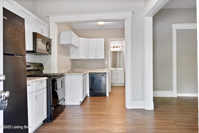 kitchen featuring a sink, wood finished floors, baseboards, white cabinets, and black appliances