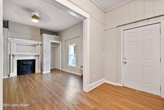 foyer entrance featuring light wood-style flooring, a fireplace, visible vents, and baseboards