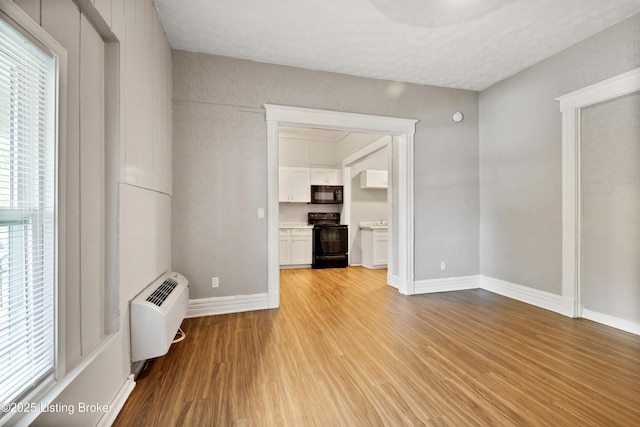 spare room featuring an AC wall unit, light wood-style flooring, and baseboards