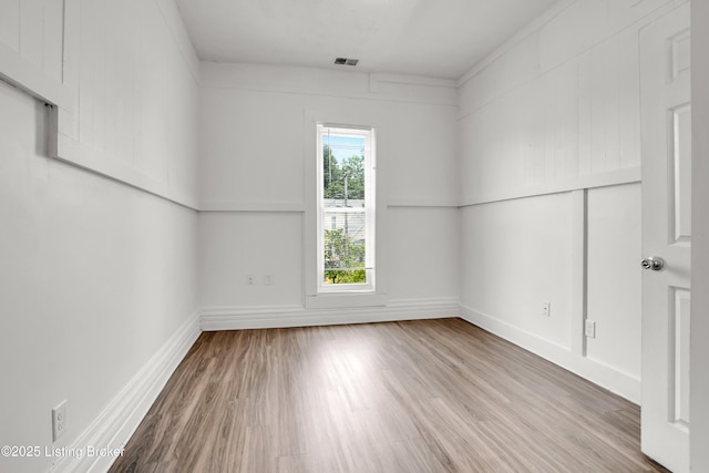 unfurnished room with wood finished floors, visible vents, and baseboards