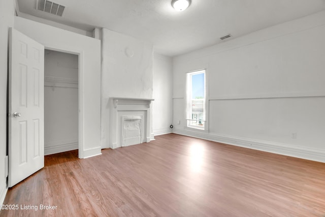 unfurnished living room featuring a fireplace, wood finished floors, visible vents, and baseboards