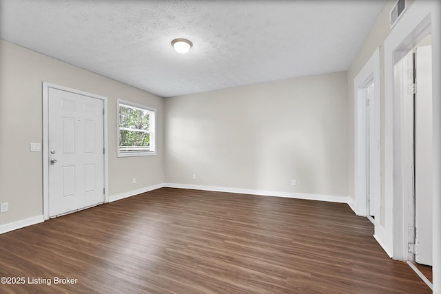 interior space featuring visible vents, dark wood finished floors, a textured ceiling, and baseboards