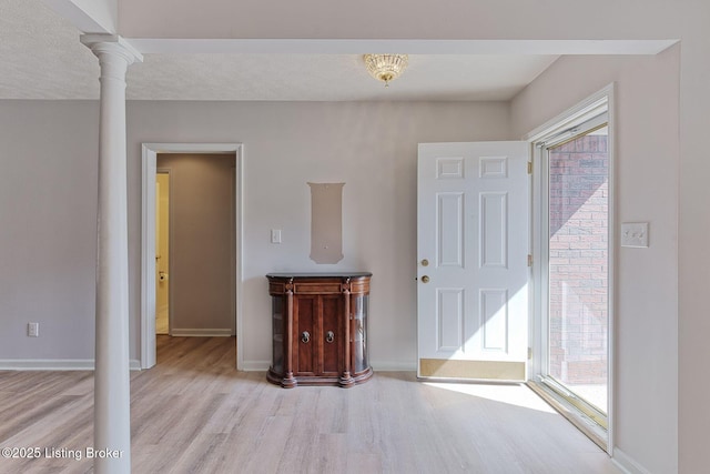 entrance foyer featuring wood finished floors, decorative columns, and baseboards