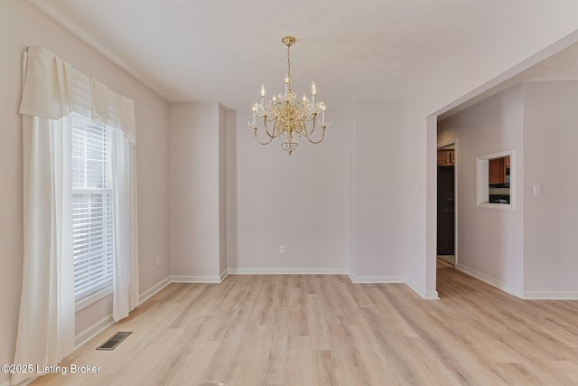 spare room featuring a chandelier, visible vents, light wood-style flooring, and baseboards