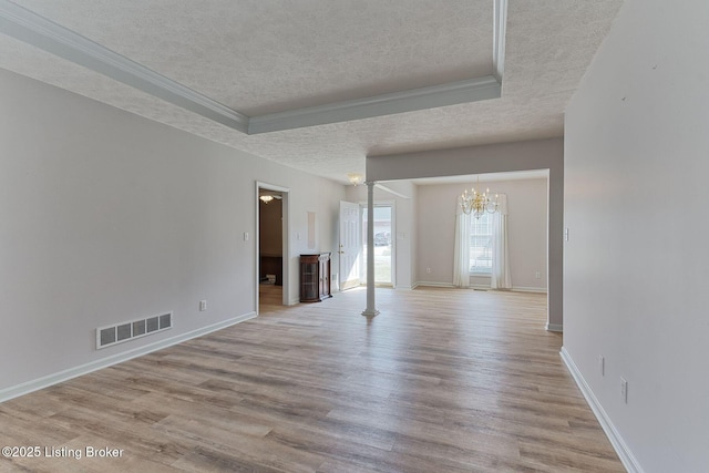 empty room featuring baseboards, visible vents, ornamental molding, wood finished floors, and a textured ceiling