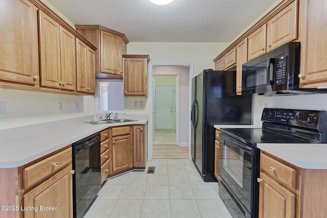 kitchen with visible vents, light countertops, a textured ceiling, black appliances, and a sink