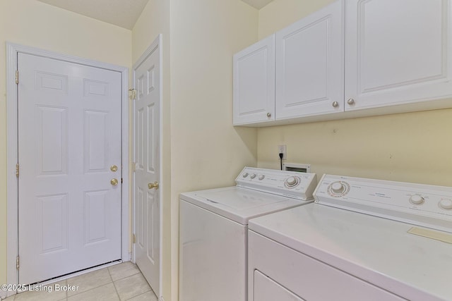 washroom featuring cabinet space, washing machine and dryer, and light tile patterned flooring