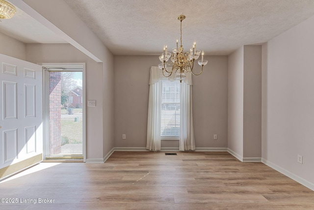 unfurnished dining area featuring light wood-type flooring, baseboards, visible vents, and a chandelier