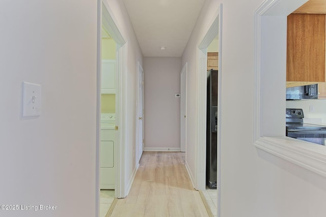 corridor with light wood finished floors, baseboards, and washer / clothes dryer