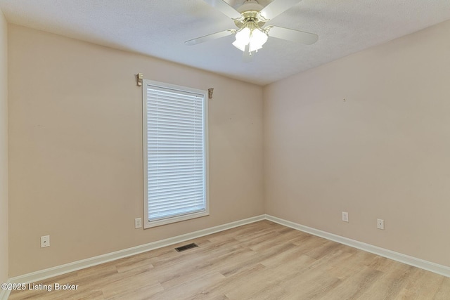 unfurnished room with light wood-type flooring, baseboards, visible vents, and a textured ceiling