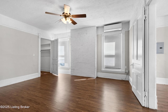 unfurnished bedroom featuring wood finished floors, electric panel, a textured ceiling, and a wall mounted AC