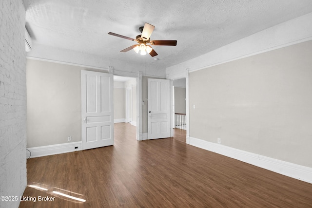 empty room with a textured ceiling, ceiling fan, wood finished floors, and baseboards