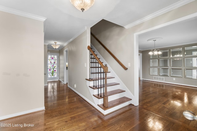 stairway featuring visible vents, a notable chandelier, wood finished floors, crown molding, and baseboards