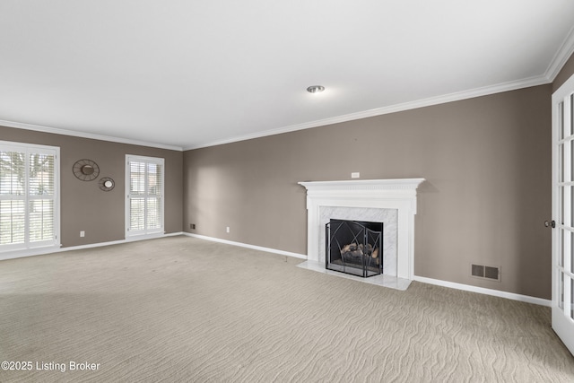 unfurnished living room featuring visible vents, baseboards, light colored carpet, ornamental molding, and a premium fireplace