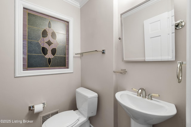 half bath with visible vents, toilet, and a sink