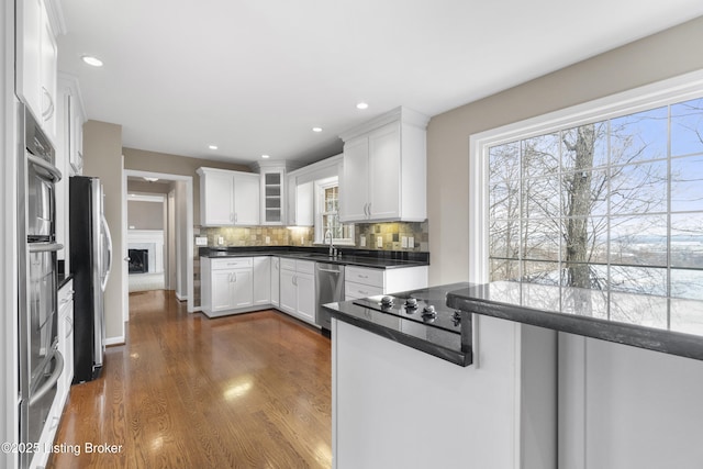 kitchen featuring dark wood-type flooring, a sink, backsplash, white cabinetry, and appliances with stainless steel finishes