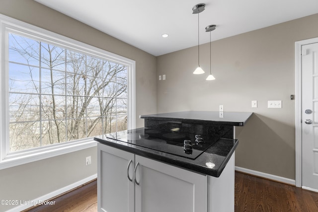 kitchen featuring dark countertops, black electric cooktop, dark wood-style flooring, and a wealth of natural light