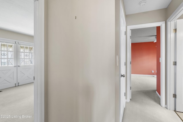 hall featuring light colored carpet and baseboards