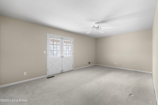 carpeted spare room with visible vents, baseboards, and a ceiling fan