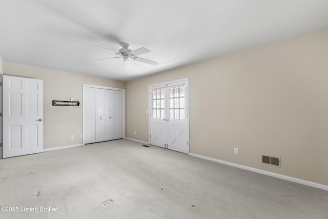 unfurnished bedroom featuring visible vents, light colored carpet, baseboards, and ceiling fan