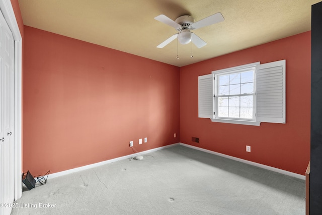 carpeted spare room with baseboards, a textured ceiling, and ceiling fan