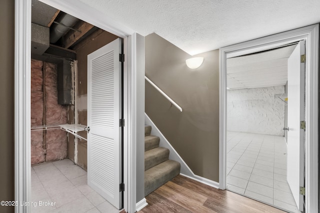 stairway with a textured ceiling and wood finished floors