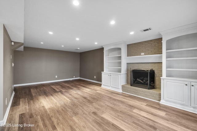 unfurnished living room with built in features, visible vents, baseboards, and wood finished floors