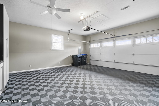 garage with visible vents, a ceiling fan, a garage door opener, and baseboards