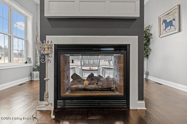 details with baseboards, visible vents, a multi sided fireplace, and wood finished floors