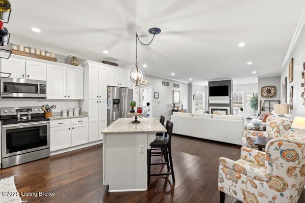 kitchen featuring ornamental molding, appliances with stainless steel finishes, white cabinetry, and a kitchen breakfast bar