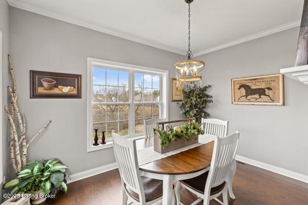 dining room with ornamental molding, dark wood-style flooring, a notable chandelier, and baseboards