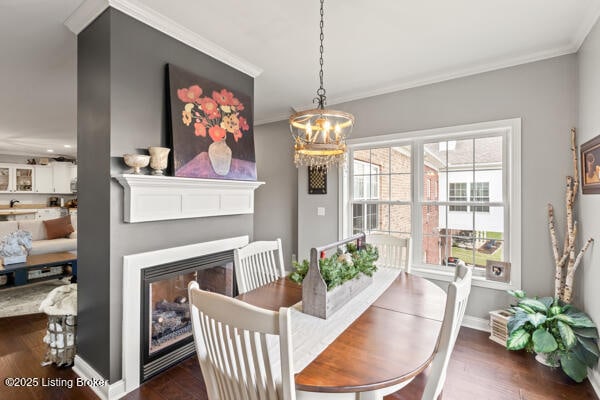 dining space featuring ornamental molding, dark wood-type flooring, a glass covered fireplace, and baseboards