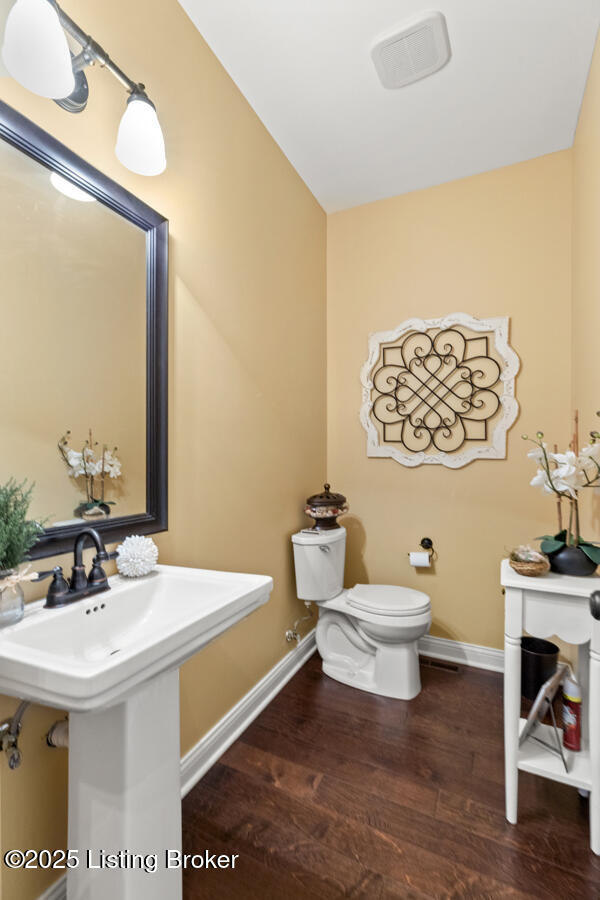 half bathroom with baseboards, a sink, toilet, and wood finished floors