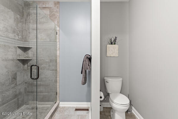 bathroom featuring visible vents, toilet, a shower stall, and baseboards