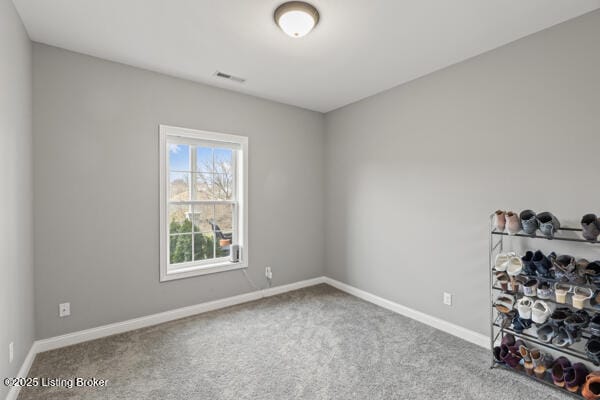 spare room with carpet floors, visible vents, and baseboards