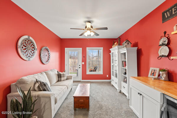 living room featuring carpet, baseboards, and a ceiling fan