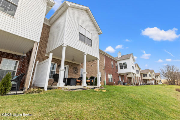 rear view of house with ceiling fan, a patio, a lawn, and brick siding